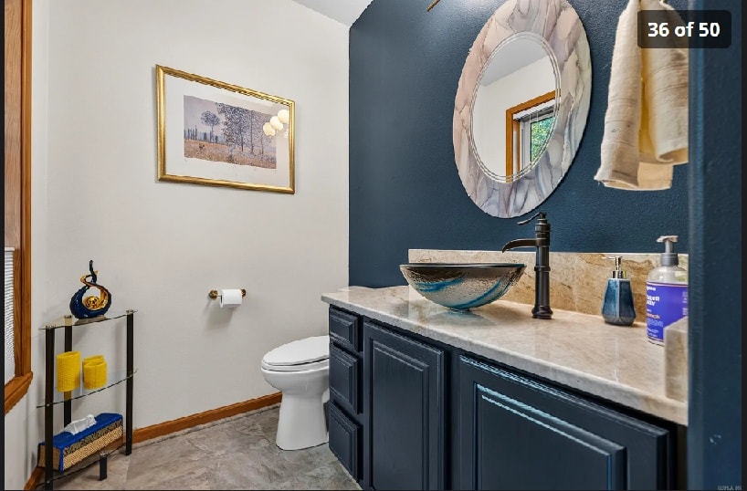 Guest bath with navy cabinetry, vessel sink, and marble countertop