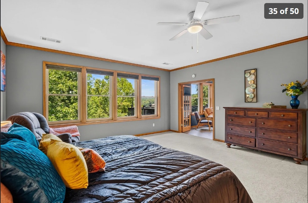 Primary bedroom with wood trim, large windows, and private deck access — 139 Waterfront Ct
